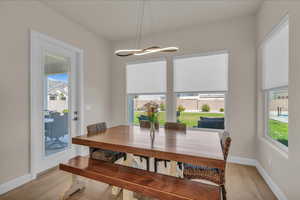 Dining space with plenty of natural light, light wood-style floors, and baseboards