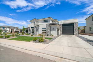 Contemporary home with stucco siding, stone siding, driveway, a residential view, and a garage