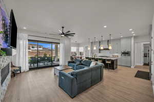 Living room with a ceiling fan, light wood-style floors, a fireplace, and recessed lighting