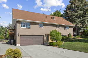 View of front of property with concrete driveway, a garage, a front lawn, brick siding, and roof with shingles