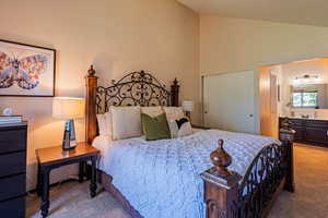 Bedroom with carpet, a closet, high vaulted ceiling, and ensuite bath