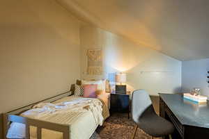 Bedroom featuring vaulted ceiling and an office area