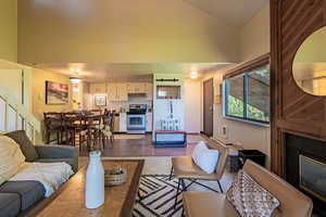 Living area featuring high vaulted ceiling, dark wood finished floors, and a glass covered fireplace