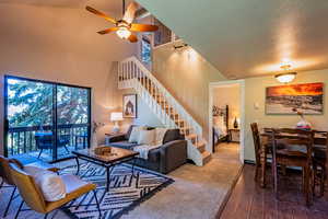 Living area with stairway, hardwood / wood-style floors, ceiling fan, and a high ceiling