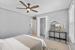Carpeted bedroom with a closet, baseboards, and ceiling fan