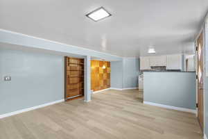 Unfurnished living room with light wood finished floors, baseboards, and built in shelves