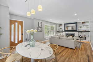 Dining space featuring light wood-type flooring, baseboards, a lit fireplace, and recessed lighting