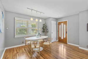 Dining space with rail lighting, light wood-style flooring, and baseboards