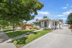 Single story home featuring an outdoor structure, a front lawn, a chimney, and a garage
