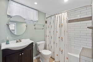 Bathroom with vanity, toilet, shower / bath combination with curtain, and recessed lighting