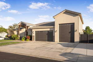 View of front facade with stucco siding, an attached garage, concrete driveway, and a tiled roof