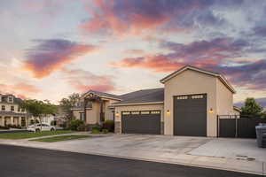 View of front of house featuring an attached garage, stucco siding, concrete driveway, stone siding, and a tiled roof