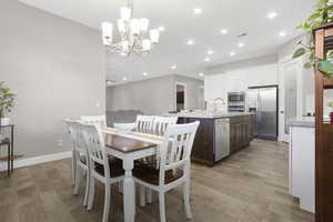 Dining room featuring light wood-type flooring, a chandelier, recessed lighting, and baseboards
