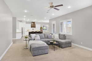 Living area featuring baseboards, light carpet, a ceiling fan, and recessed lighting