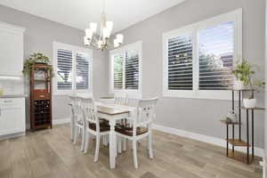 Dining space with a chandelier, light wood finished floors, and baseboards