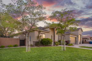 View of front facade with stucco siding, concrete driveway, an attached garage, and a gate