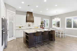 Kitchen with premium range hood, a sink, a chandelier, white cabinetry, and recessed lighting
