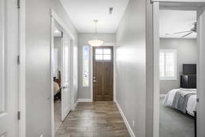 Foyer with light wood-style flooring, ceiling fan, and baseboards