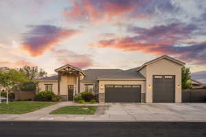 View of front facade featuring a garage, concrete driveway, stucco siding, a tile roof, and stone siding