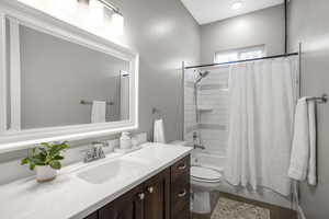 Full bath with vanity, toilet, and shower / bathtub combination with curtain