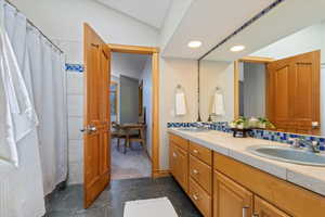 Bathroom featuring double vanity, vaulted ceiling, and recessed lighting
