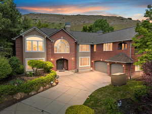 View of front of house featuring driveway, a chimney, an attached garage, a mountain view, and roof with shingles