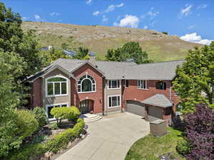 View of front facade with concrete driveway, a chimney, a garage, brick siding, and a mountain view