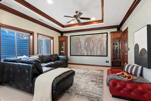 Home theater room featuring carpet, a ceiling fan, ornamental molding, a raised ceiling, and recessed lighting