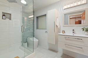 Full bath featuring vanity, a stall shower, toilet, and tile patterned flooring