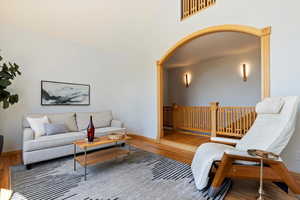 Living room featuring wood finished floors, arched walkways, baseboards, and a towering ceiling