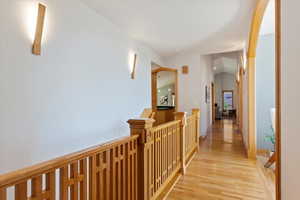 Hallway with light wood-style flooring and an upstairs landing
