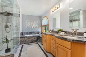 Full bath with a bath, inlaid floor details, a shower stall, and vanity