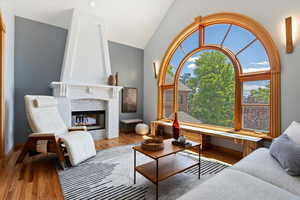 Living area featuring vaulted ceiling, wood finished floors, and a tiled fireplace