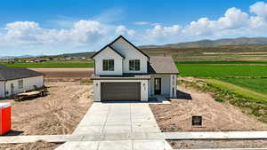Modern farmhouse featuring a mountain view, driveway, an attached garage, and a view of rural / pastoral area