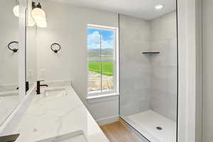 Full bathroom featuring vanity, plenty of natural light, baseboards, and tiled shower