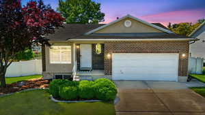 View of front of home featuring concrete driveway, a shingled roof, brick siding, and a garage