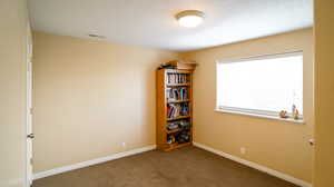 Sixth bedroom/spare room featuring dark colored carpet and baseboards