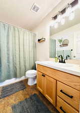 Full bathroom with toilet, vanity, a textured ceiling, and a shower with curtain