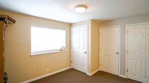 Unfurnished sixth bedroom with dark colored carpet and baseboards