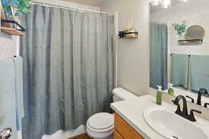 Full master bathroom with toilet, vanity, and curtained shower