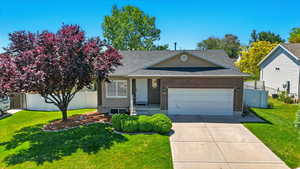 View of front facade with a shingled roof, a garage, concrete driveway, and brick siding