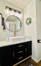 Bathroom with vanity, backsplash, a textured ceiling, and baseboards