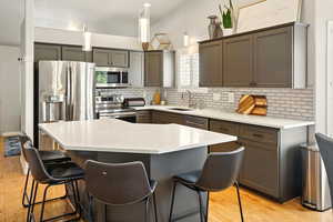 Kitchen with stainless steel appliances, a sink, backsplash, and a kitchen bar