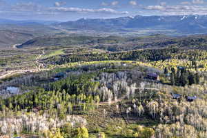 Aerial view of property's location featuring a mountainous background and a heavily wooded area