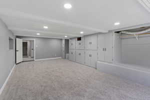Finished below grade area featuring light colored carpet, recessed lighting, and baseboards