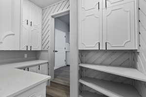 Interior space with white cabinetry, light stone countertops, and wood finished floors