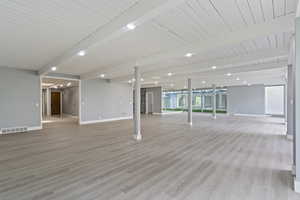 Interior space with beamed ceiling, baseboards, light wood-type flooring, and healthy amount of natural light