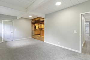 Unfurnished living room featuring beam ceiling, baseboards, light colored carpet, a sink, and recessed lighting
