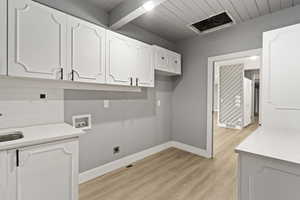 Washroom featuring washer hookup, light wood finished floors, baseboards, cabinet space, and wooden ceiling