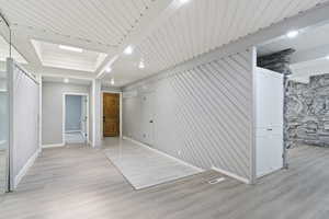 Unfurnished bedroom with baseboards, light wood finished floors, and beamed ceiling